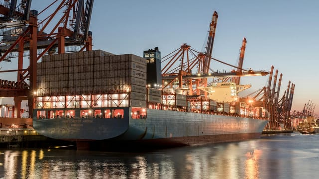 A container ship docked at Hamburg port during dusk, showcasing global trade activity.