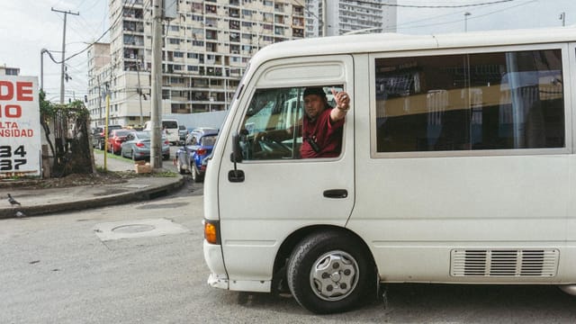 City view with a driver in a white van on bustling streets of Cidade do Panamá.