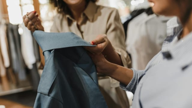 Women examining a blue garment in a modern boutique, highlighting a shopping experience.