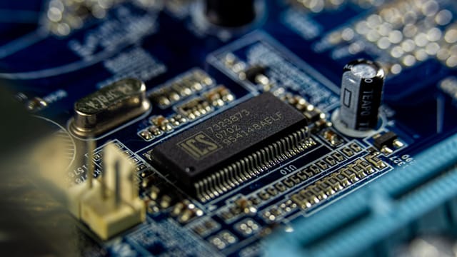 Detailed shot of a microprocessor on a blue motherboard showcasing electronic components.