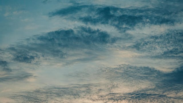 Spectacular view of fluffy clouds floating high in air on bright sky in nature at sundown time on summer evening