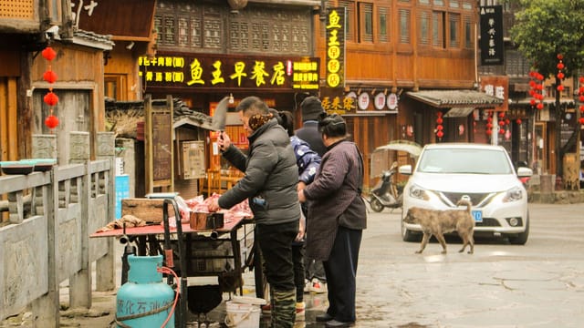 A vibrant street market in Qiandongnan Prefecture with local vendors and shoppers.