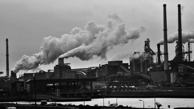 A black and white view of the industrial area in Rotterdam with smoke emissions.