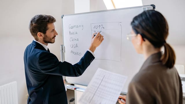Business professionals in a meeting discussing strategies on a whiteboard.