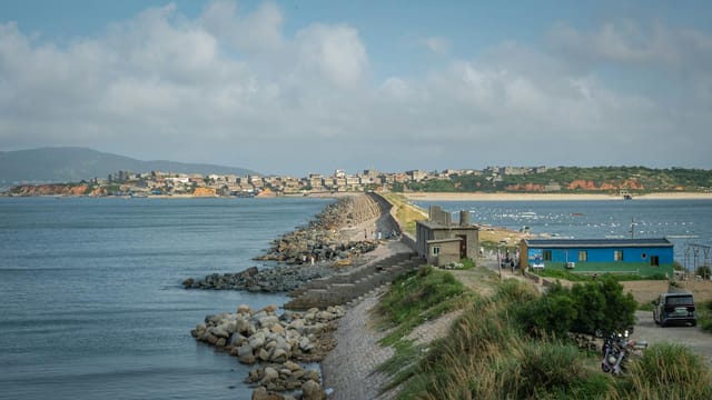 Explore the picturesque coastal breakwater in Fuzhou, China, surrounded by serene ocean views and distant townscape.