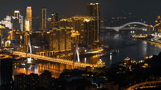A breathtaking view of Chongqing cityscape at night, featuring illuminated skyscrapers and bridges over the river.