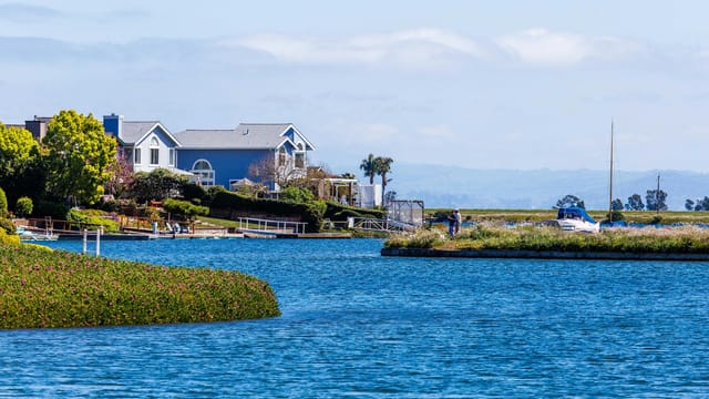 Charming lakeside house with a beautiful waterfront view, surrounded by greenery and serene water.