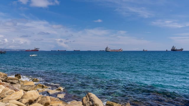 Tranquil view of the Mediterranean Sea with tankers and rocky shore in Limassol, Cyprus.