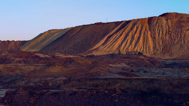 A striking view of a mining site showcasing rugged hills and mineral textures at sunset.