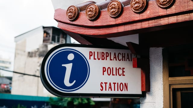 Close-up view of Plubplachai Police Station sign with traditional architectural details in Bangkok.