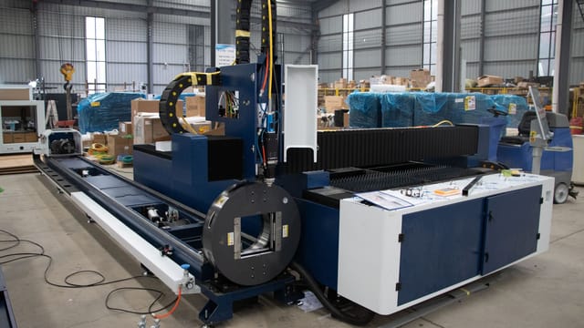 A large industrial laser cutter inside a warehouse in Jinan, China, showcasing advanced machinery.