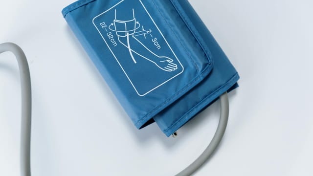 Close-up of a blue blood pressure cuff on a white surface, medical equipment for health monitoring.