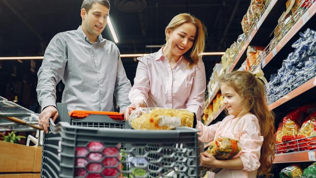 A joyful family of three shopping together in a supermarket, creating a memorable experience.