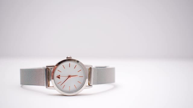 Close-up of a silver wristwatch with precision details on a minimalist background.