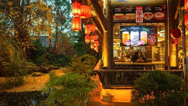 A cozy Chinese restaurant by the river with red lanterns glowing warmly at night in Chengdu, China.