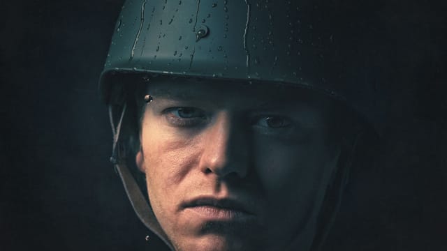 Intense portrait of a soldier wearing a helmet, captured in moody lighting.