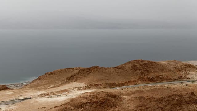 Aerial view of foggy mountains overlooking the tranquil Dead Sea in Israel.