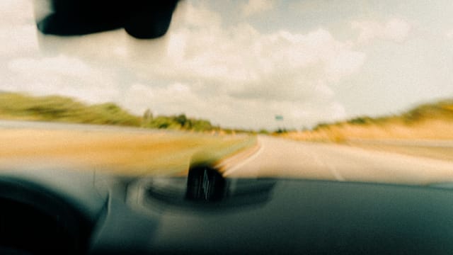 Illustrative image: Dynamic blurred image from a vehicle's windshield capturing a rural road in motion.