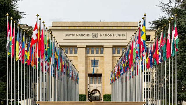 View of the United Nations Office in Geneva adorned with flags of various countries.