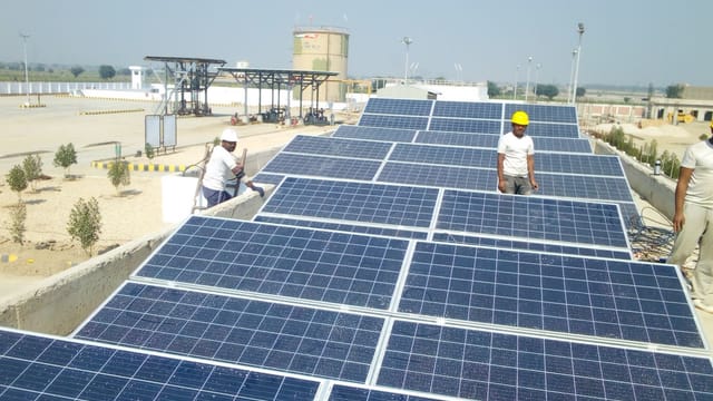 Workers installing solar panels on a rooftop for renewable energy generation.