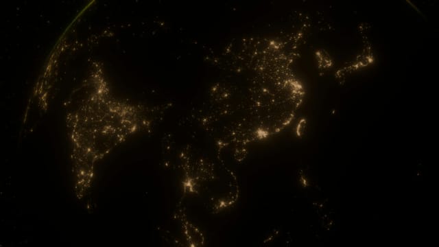 Glowing city lights of Asia on the dark side of Earth from space.