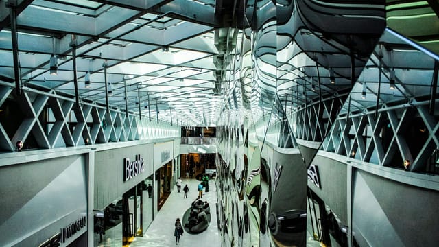 A contemporary shopping mall hallway with glass reflections and modern architecture.