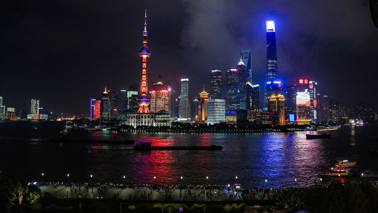 Illuminated Shanghai skyline with reflections on Huangpu River at night.
