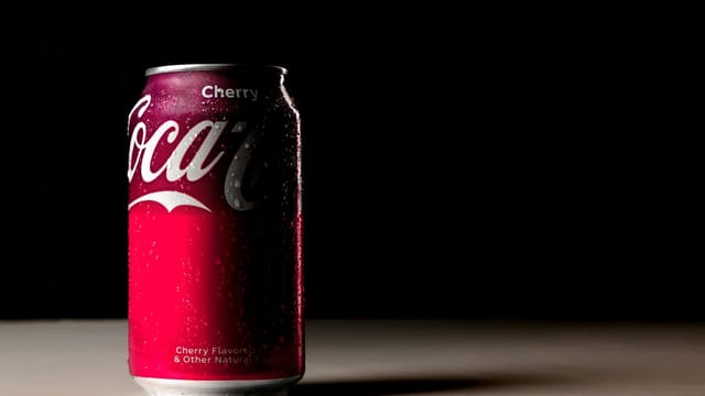 Cherry flavored cola can with dew drops in a dark artistic composition.
