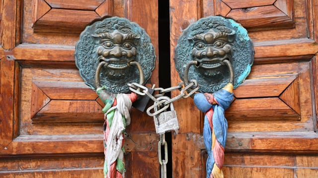 Close-up of a locked Tibetan door with bronze lion ornaments in Ganzi, China.