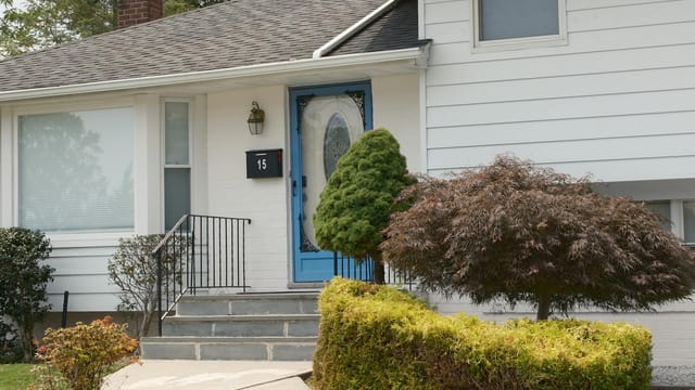 Inviting suburban home with a distinctive blue front door and well-kept shrubs.