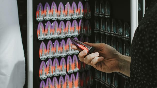 A hand holding a colorful magnet in a souvenir shop in Dubai, United Arab Emirates.
