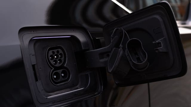 Close-up image of an electric vehicle charging port on a black car.