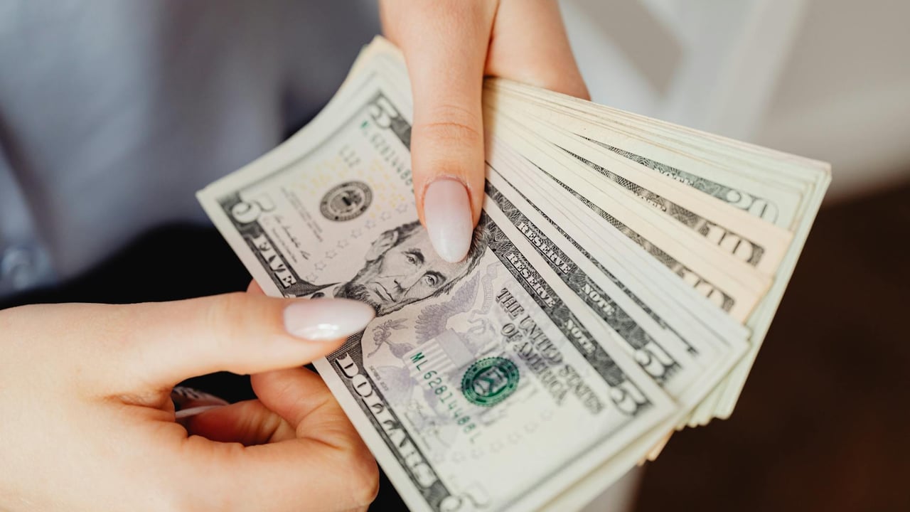 Hands count US dollar bills, showcasing finance and cash handling concepts.