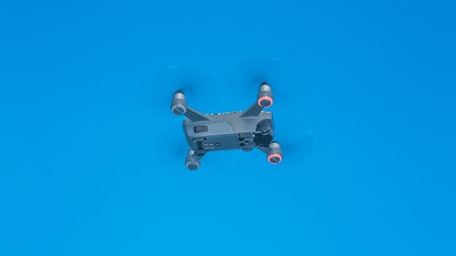 From below of side part of remote control drone with quickly spinning propellers and small cameras for taking photos and videos
