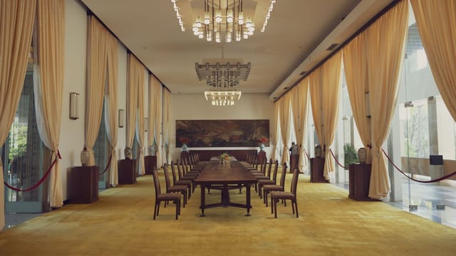 Spacious banquet room with luxury decor in Reunification Palace, featuring elegant chandeliers and long dining table.