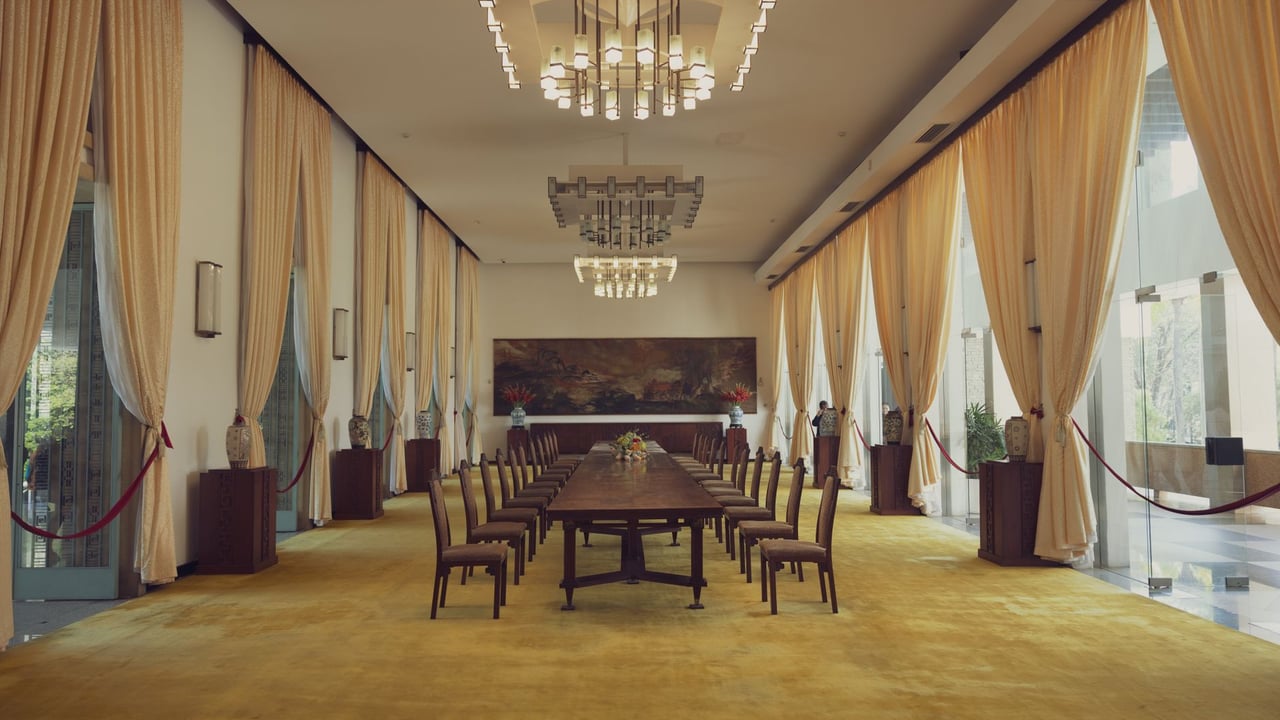 Spacious banquet room with luxury decor in Reunification Palace, featuring elegant chandeliers and long dining table.