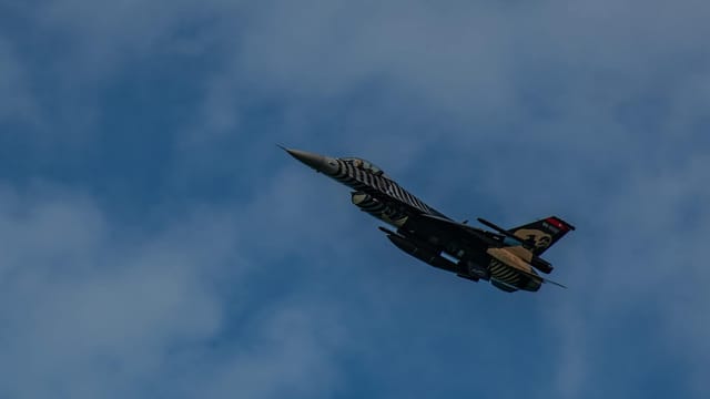 A striking image of an F-16 jet soaring in a clear blue sky.