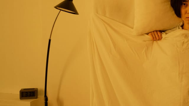 A woman lying awake in bed at 3:33 a.m., showcasing insomnia issues.