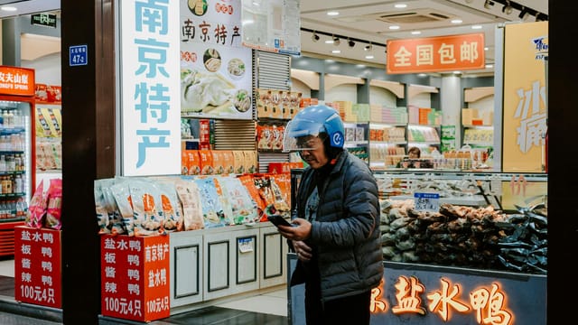 Explore the bustling urban life of Nanjing with this vibrant street market scene featuring local shops and a passerby.