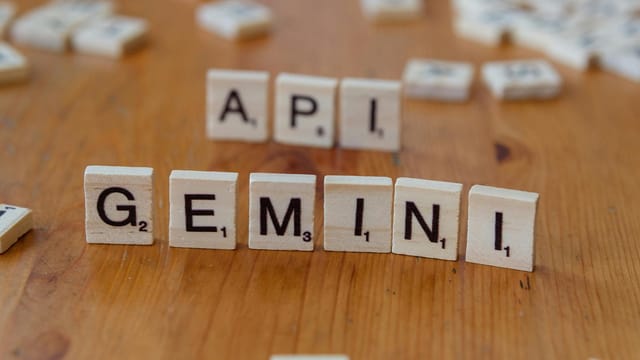 Close-up of Scrabble tiles forming the words 'API' and 'GEMINI' on a wooden surface.