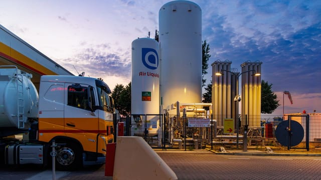 A vibrant sunset over a fueling station with tanks and trucks in Rotterdam, Netherlands.