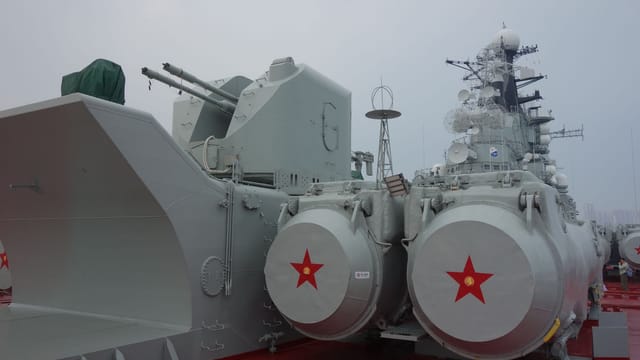 Detailed view of military battleship turret and radar on a cloudy day