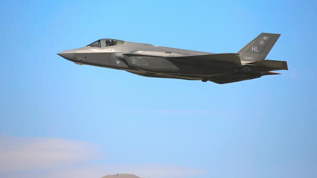 A sleek F-35A military jet flying against a clear blue sky in Nevada.