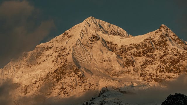 Captivating view of a snow-capped mountain peak glowing under the sunset light, creating a serene winter landscape.