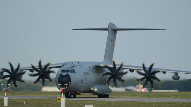 A German military Airbus A400M aircraft sits on a runway, showcasing its immense size and powerful engines.