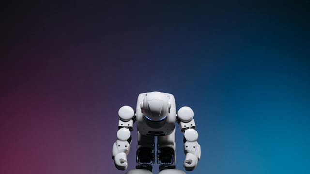 White robot in a bowing pose against a gradient studio background.