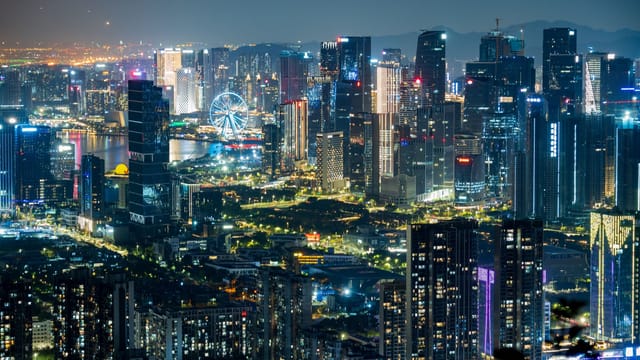 Dazzling city skyline illuminated at night showcasing modern skyscrapers and a Ferris wheel.