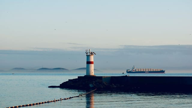 Lighthouse and cargo ship at Bosphorus Strait, Istanbul during the day.
