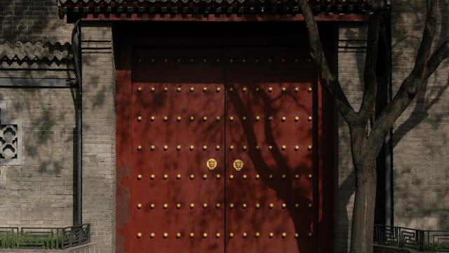 A historic red gate with gold studs, reflecting traditional Chinese architecture and culture.