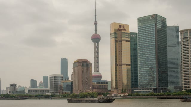 Moody view of Shanghai's Pudong skyline with the iconic Oriental Pearl Tower on a cloudy day.